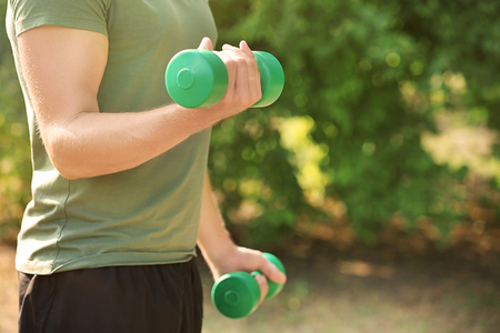 Sporty young man training with dumbbells outdoorsの写真素材