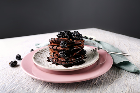 Plate with tasty chocolate pancakes and berries on light wooden tableの写真素材