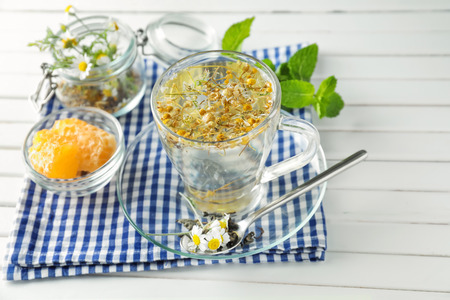 Cup of delicious camomile tea and honeycombs on wooden tableの写真素材