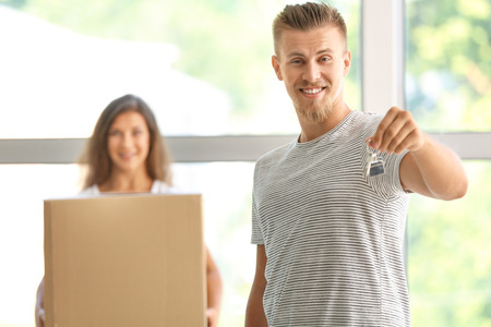 Happy young man with key after moving into new house