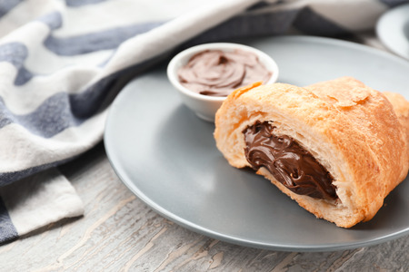Tasty croissant with chocolate cream on plate, closeupの写真素材