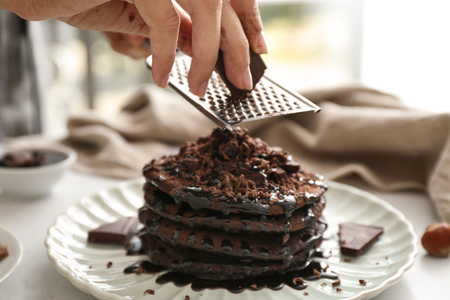 Woman grating chocolate over tasty pancakes, closeupの写真素材