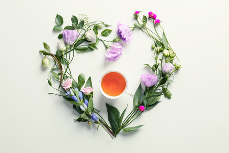 Flat lay composition with beautiful flowers and cup of tea on white backgroundの写真素材