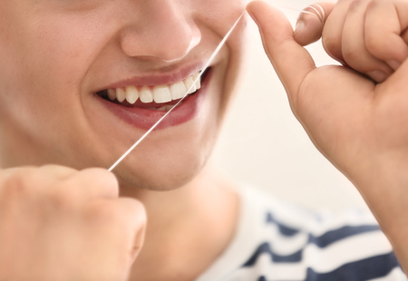 Young man flossing teeth, closeup