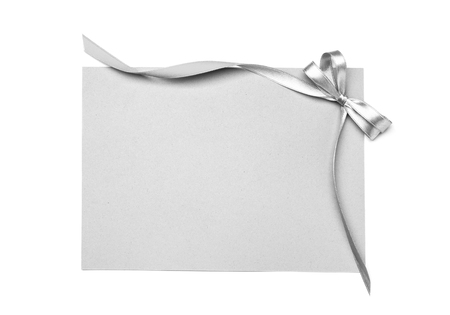 Blank paper card with silver ribbon and bow on white backgroundの写真素材