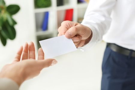 Man giving business card to woman in office, closeupの写真素材