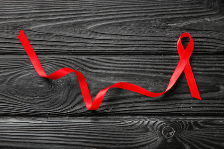 Red ribbon on wooden background. AIDS conceptの写真素材
