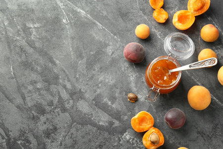 Jar with delicious apricot jam and fresh fruit on grunge tableの写真素材