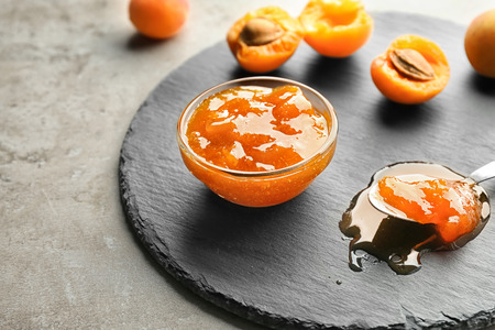 Bowl with delicious apricot jam on slate plateの写真素材