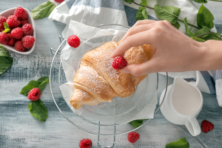 Woman decorating croissant with raspberry, closeupの写真素材