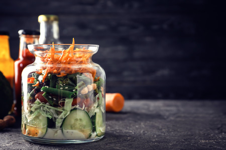 Delicious vegetable salad in mason jar on dark tableの写真素材