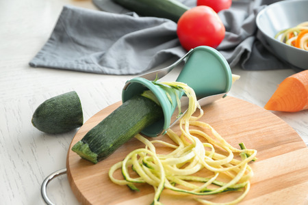 Fresh zucchini spaghetti with spiral grater on wooden boardの写真素材
