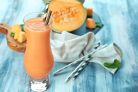 Glass of fresh melon smoothie on wooden tableの写真素材