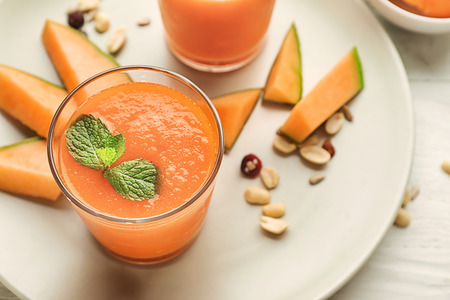 Glass with delicious melon smoothie on plate, closeupの写真素材