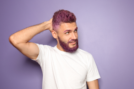 Portrait of handsome man with dyed hair and beard on color backgroundの写真素材