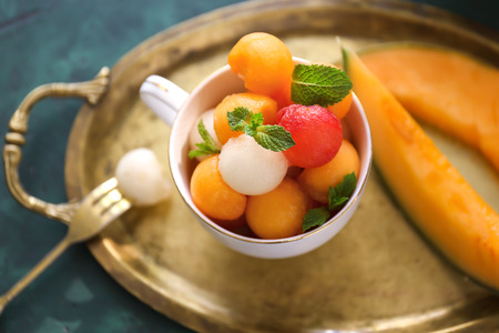 Cup with tasty melon balls on tableの写真素材
