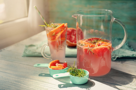 Fresh grapefruit cocktail with rosemary in glassware on white tableの写真素材