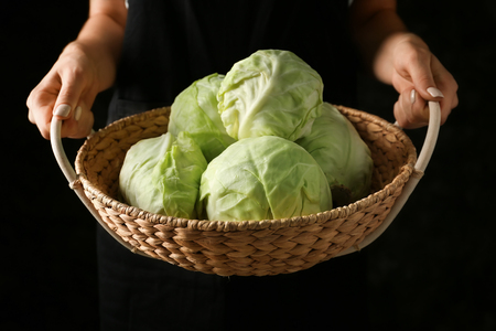 Woman holding basket with cabbage on dark background, closeupの写真素材