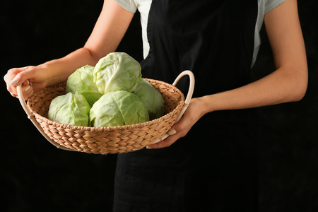 Woman holding basket with cabbage on dark backgroundの写真素材