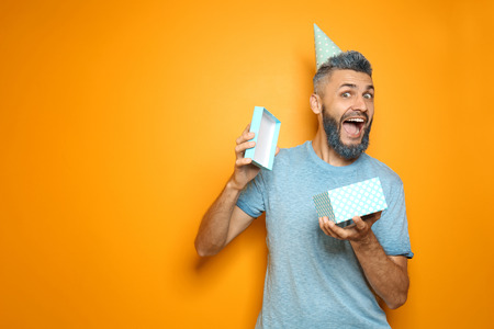 Portrait of emotional man with Birthday gift on color backgroundの写真素材