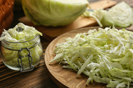 Plate and glass jar with cut cabbage on wooden table, closeupの写真素材