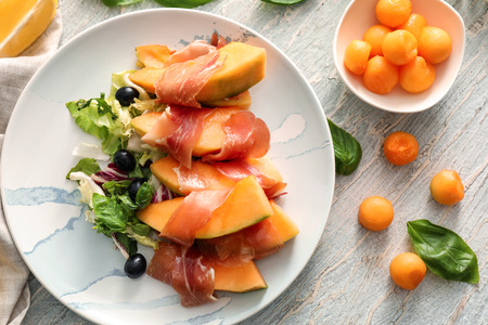 Delicious melon wrapped in prosciutto on plateの写真素材