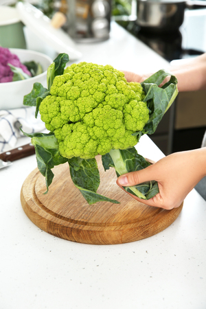 Woman holding green cauliflower in kitchen, closeupの写真素材