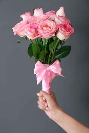 Woman holding bouquet of beautiful roses on grey backgroundの写真素材