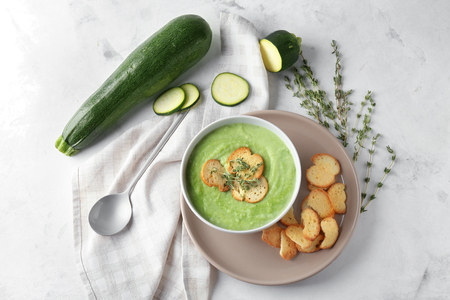 Tasty zucchini soup with croutons in bowl on light tableの写真素材