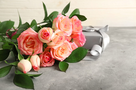 Beautiful roses with gift box on grey tableの写真素材
