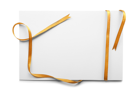 Blank sheet of paper with golden ribbon on white backgroundの写真素材