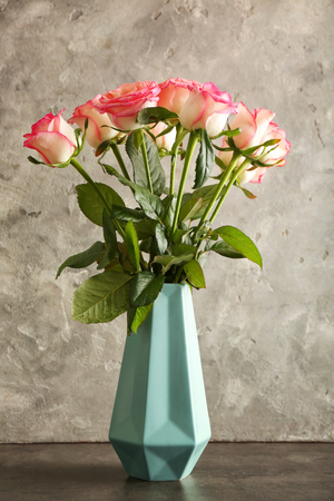 Vase with beautiful roses on grey backgroundの写真素材
