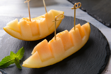 Sliced ripe melon on slate plateの写真素材