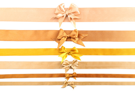 Golden ribbons with beautiful bows on white backgroundの写真素材