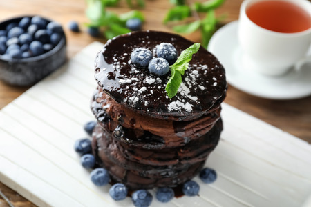 Tasty chocolate pancakes with blueberries on white boardの写真素材