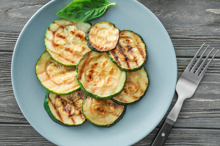 Plate with tasty grilled zucchini on wooden tableの写真素材