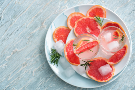 Fresh grapefruit cocktail with rosemary in glasses on platesの写真素材