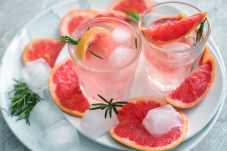 Fresh grapefruit cocktail with rosemary in glasses on platesの写真素材