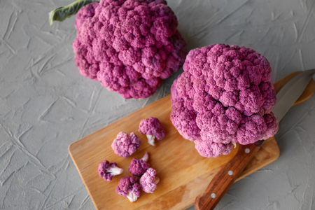 Cutting board with purple cauliflower on grey backgroundの写真素材
