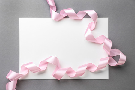 Blank paper card with pink ribbon on grey backgroundの写真素材