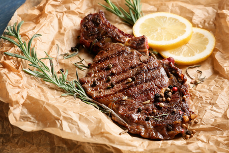 Tasty grilled steak with sliced lemon and spices on parchmentの写真素材