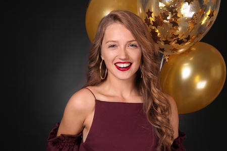 Beautiful young woman with balloons on dark backgroundの写真素材