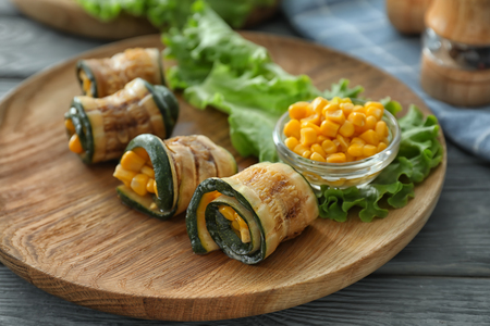 Tasty zucchini rolls with corn on wooden plateの写真素材