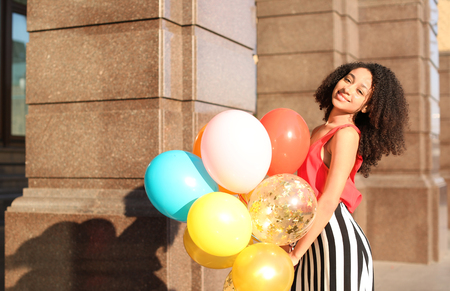Beautiful African-American woman with balloons outdoorsの写真素材
