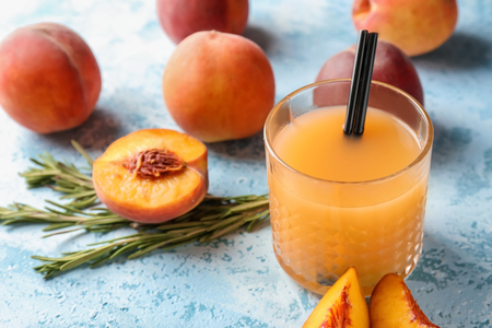 Peach juice in glass on color tableの写真素材