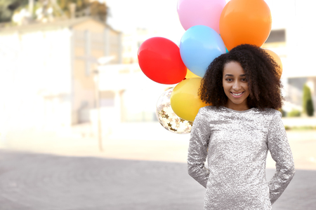 Beautiful African-American woman with balloons outdoorsの写真素材