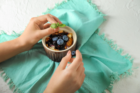 Woman with delicious blueberry dessert on light tableの写真素材