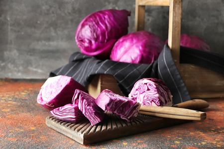 Crate and board with sliced red cabbage on color tableの写真素材
