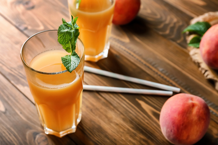 Peach juice in glass on wooden tableの写真素材