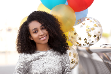 Beautiful African-American woman with balloons outdoorsの写真素材